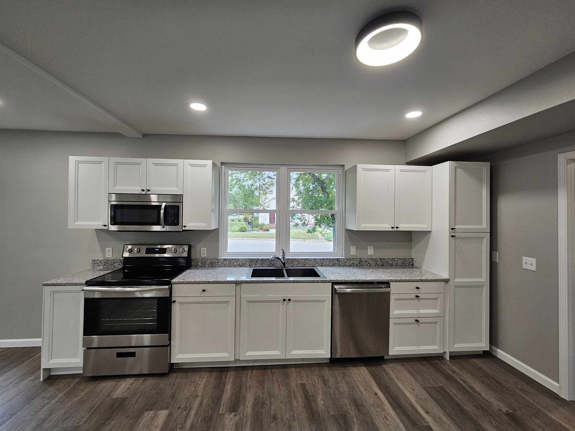 Modern kitchen with white cabinets, granite counters, and stainless steel appliances