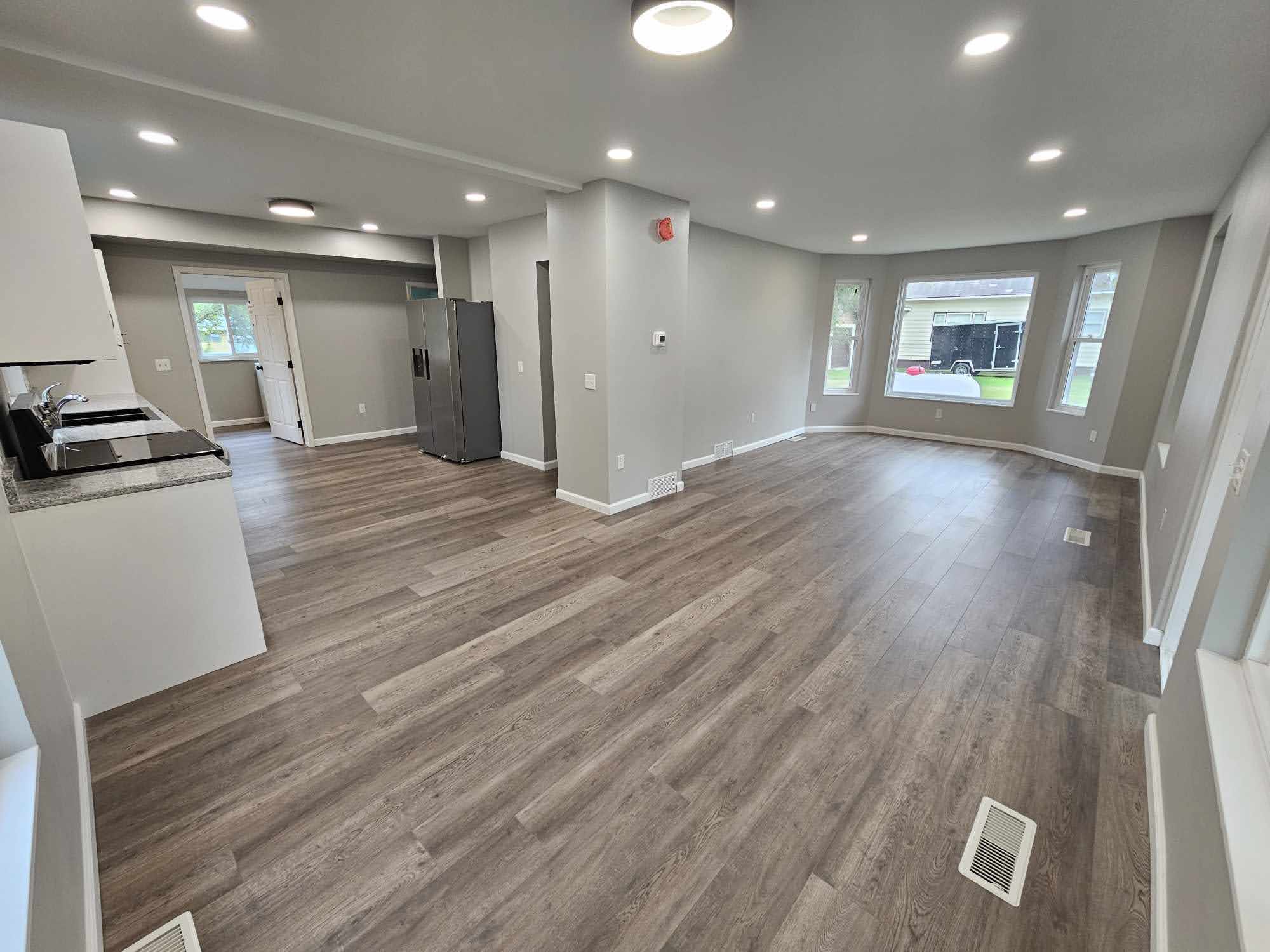 Open floor plan living area with bay window and recessed lighting